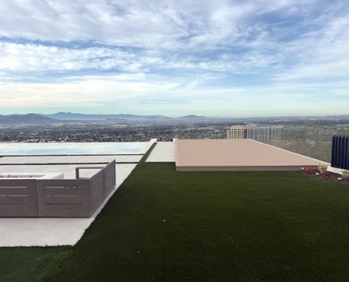 A pristine artificial turf area leading to a modern terrace with a vast mountain backdrop.