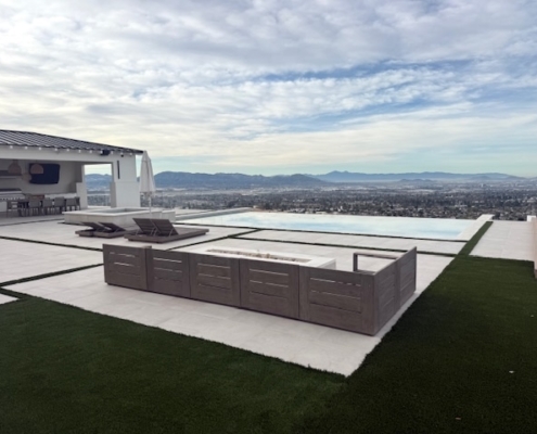 Low-profile outdoor sectional sofa surrounding a linear fire pit on a modern stone patio.